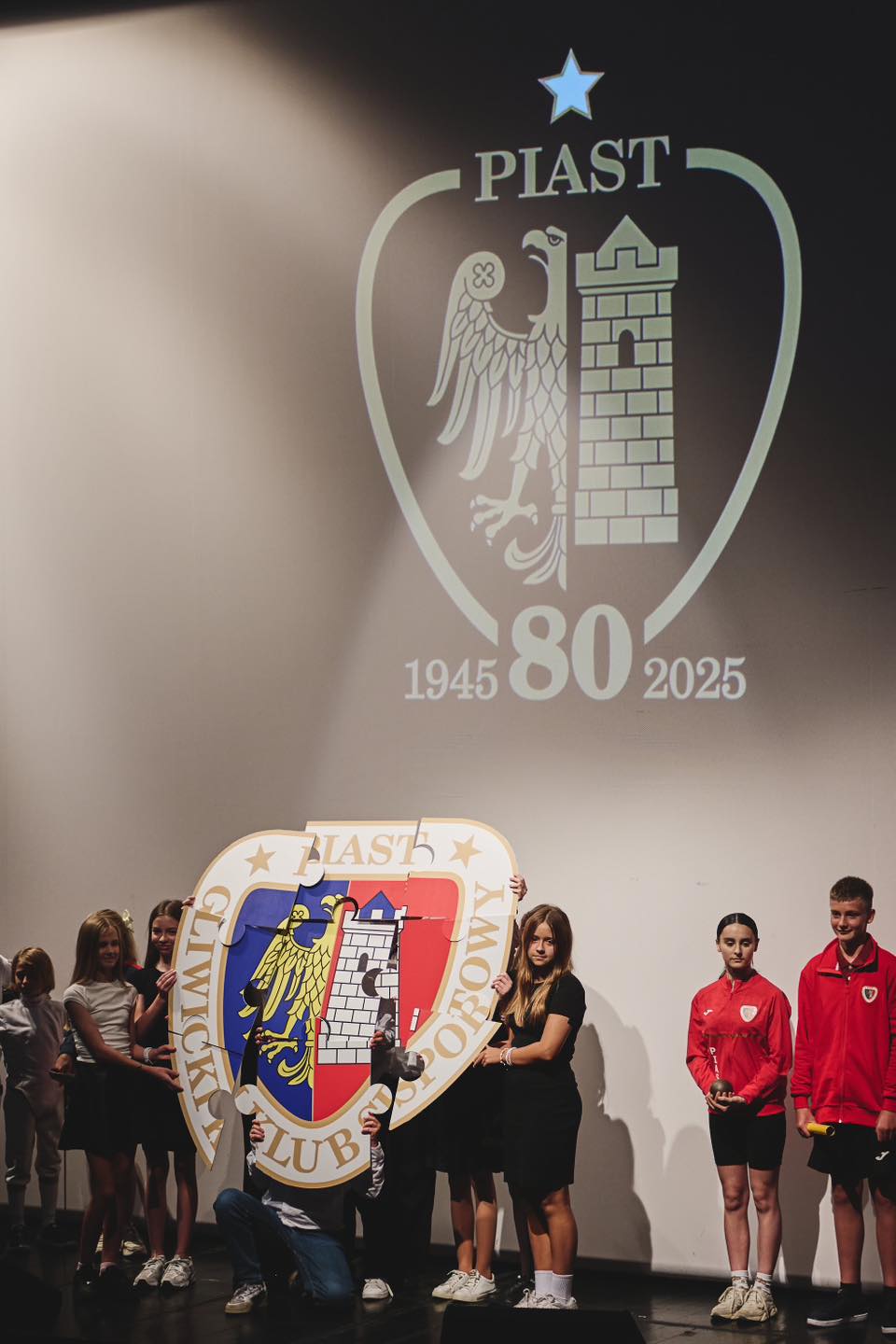 Fot. M.Buksa/UM Gliwice młodzi ludzie na scenie, na ekranie herb Piasta