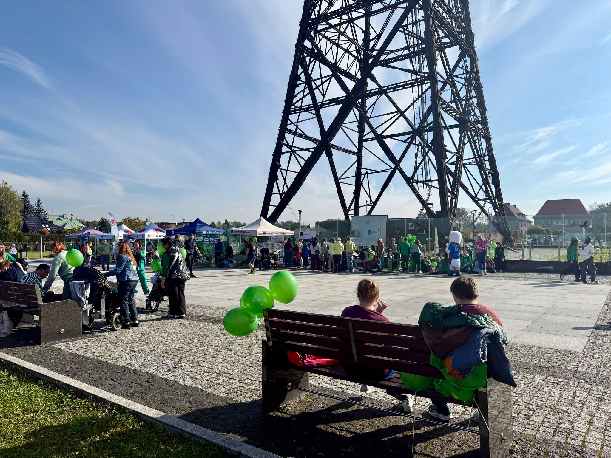 radiostacja i ludzie na ławce z zielonymi balonami