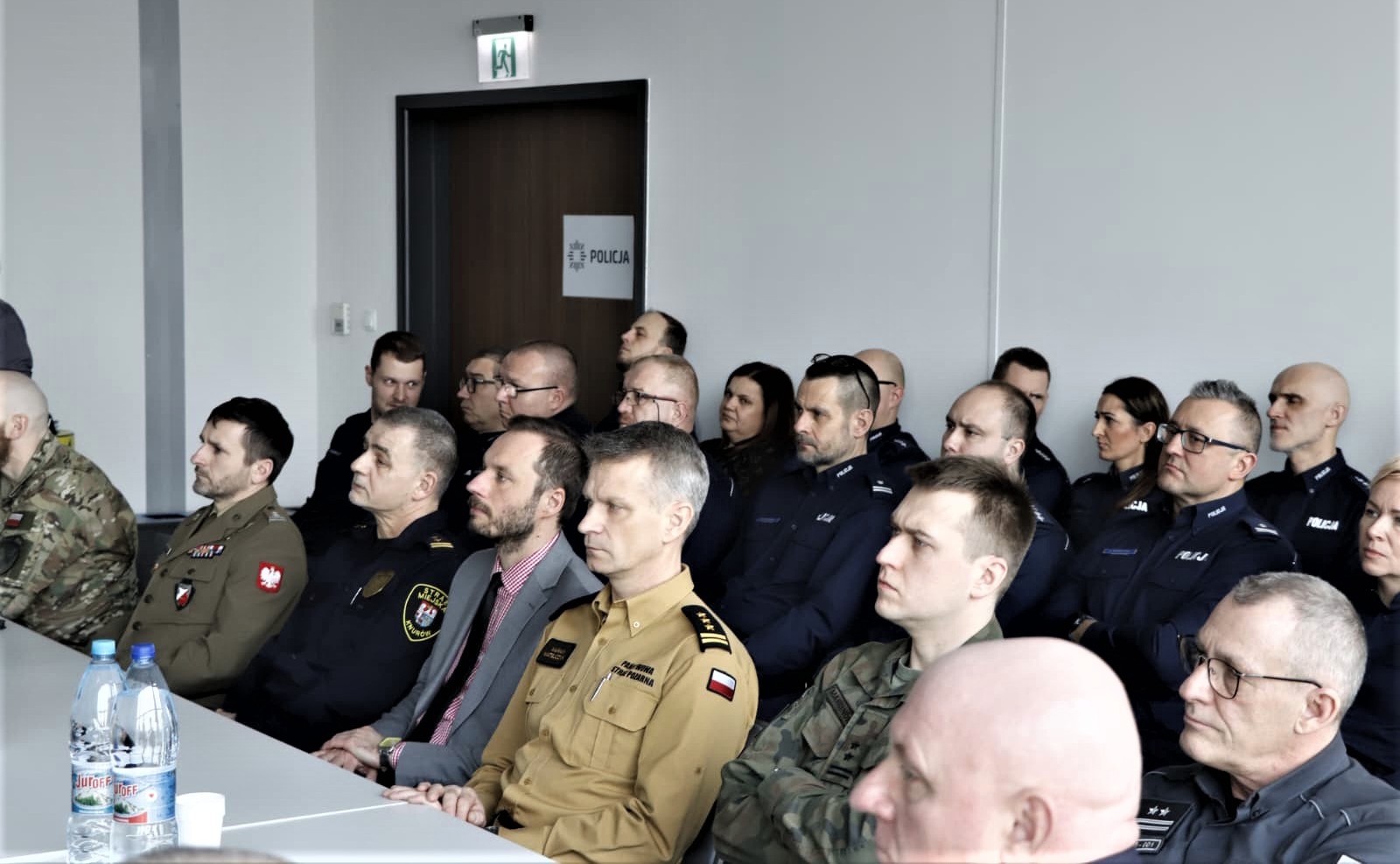 ludzie w sali siedzą na krzesłach