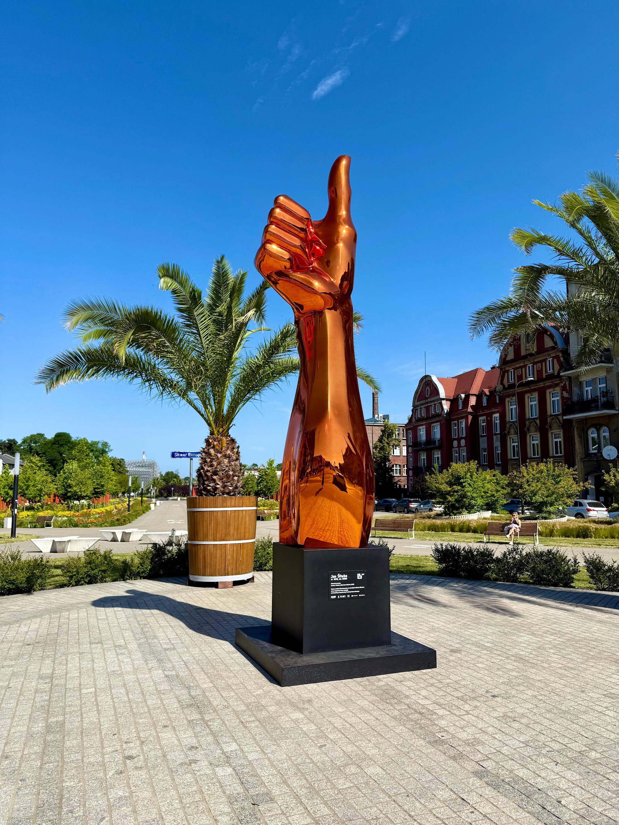 totem w kształcie kciuka na skwerze Europejskim. W tle palma