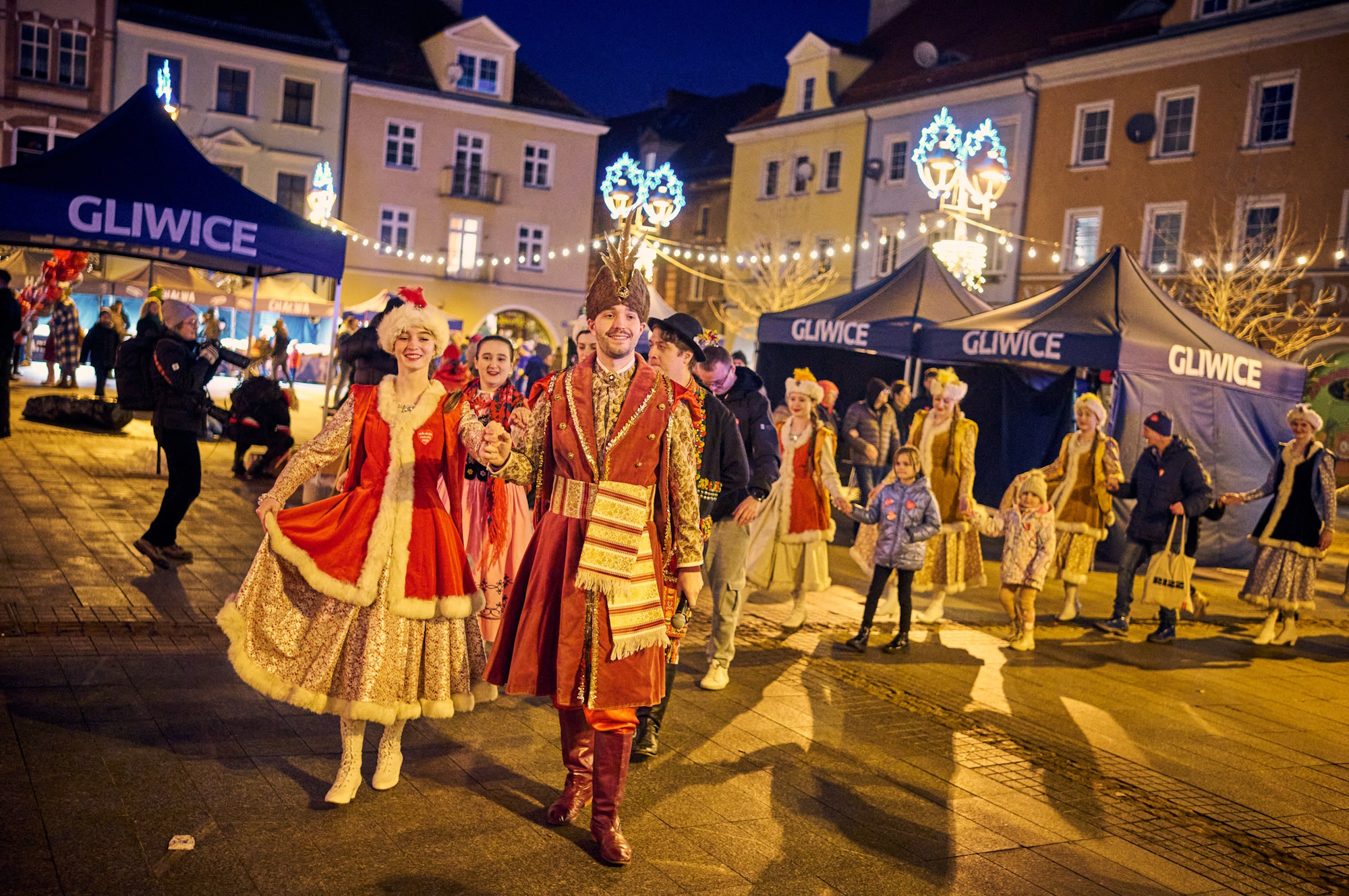 Ludzie w historycznych przebraniach tańczą poloneza na Rynku